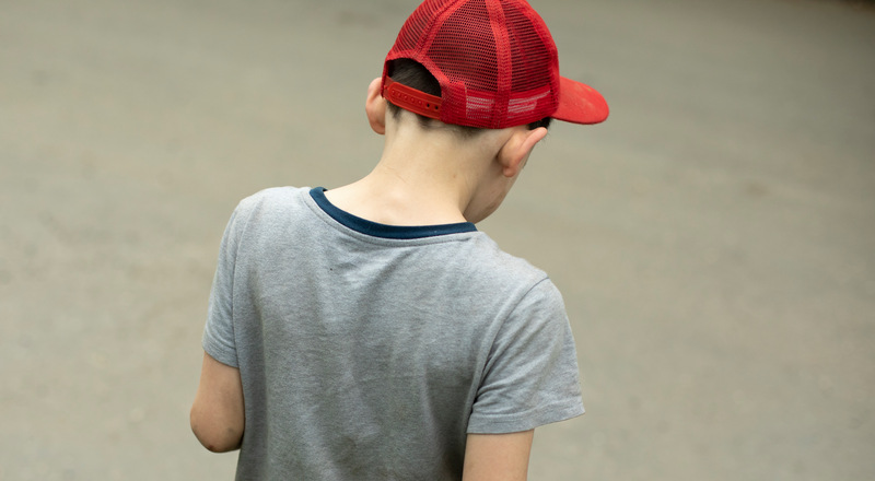 Ryggen på en pojke med röd keps. Foto.