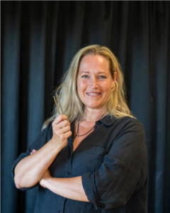 Blond kvinna håller i stämgaffel. Foto.