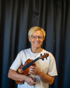 Kortklippt kvinna håller i fiol. Foto.