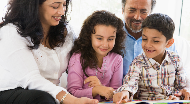 Två vuxna och två barn tittar i en bok