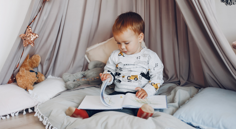 Liten pojke sitter i en koja och tittar i en bok