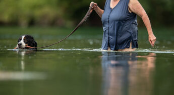 Äldre kvinna badar med sin hund.