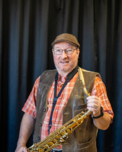 Man med keps och saxofon. Foto.