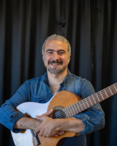 Man håller i gitarr. Foto.