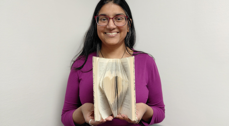 Kvinna håller upp en en öppen bok och visar sin bokvikning