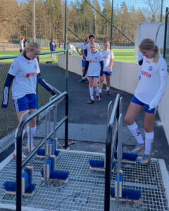 Fotbollsspelare borstar av skorna vid en bortsstation.
