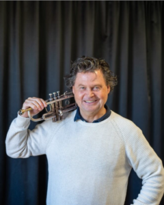 Glad man håller i trumpet. Foto.