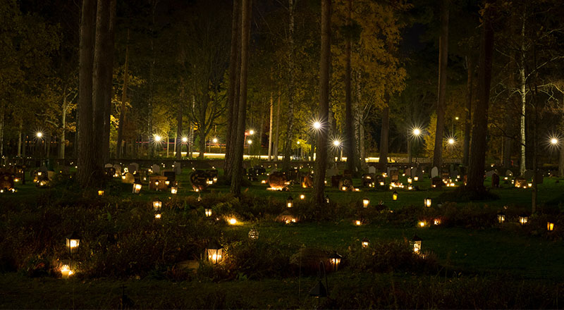 Tända ljus på gravar på en Griftegård en mörk kväll.