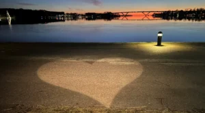 Hjärtformad belysning på strandpromenaden vid Motalaviken. Motalabron i bakgrunden. Foto.