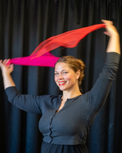 Mörkhårig kvinna dansar med sjalar i händerna. Foto.