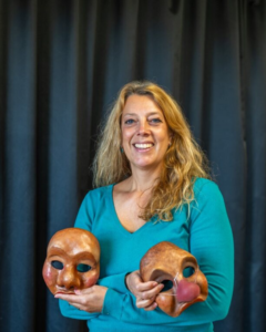 Kvinna håller i teatermasker. Foto.