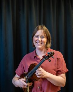 Glad kvinna håller i fiol. Foto.