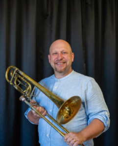 Man håller i stort mässingsinstrument. Foto.