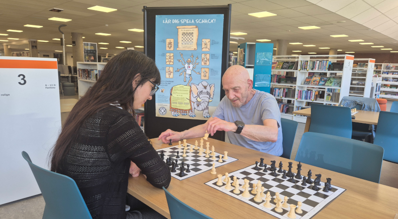 En kvinna och en man spelar schack i bibliotekets lokaler