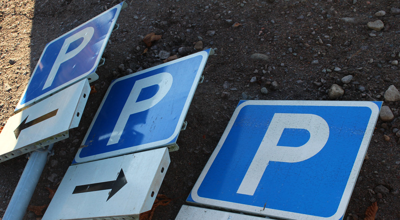 Tre skyltar som visar parkering som ligger på marken. Foto.