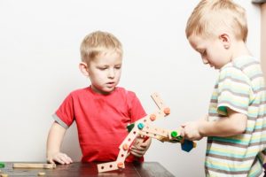 två pojkar hjälps åt att sätt ihop trädelar i leksak