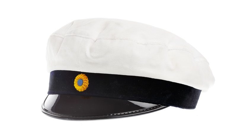 Vit studentmössa med svart kant och skärm. I mitten av den svarta kanten syns ett blågult märke.