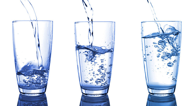 Tre vattenglas som fylls med vatten.