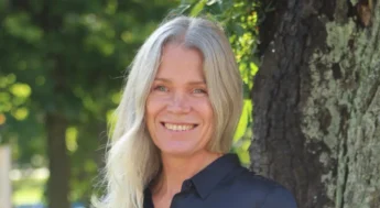 Blond kvinna står i parken utanför kommunhuset i mitten på september.foto.