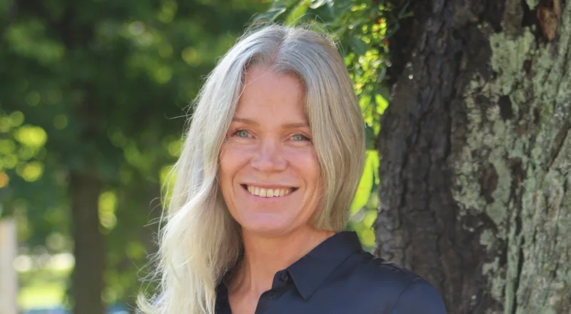 Blond kvinna står i parken utanför kommunhuset i mitten på september.foto.